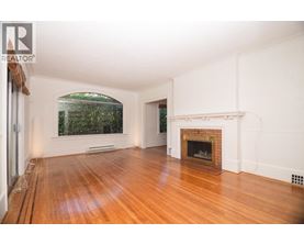 A large empty room with a fireplace and a window.