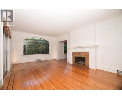 A large empty room with a fireplace and a window.