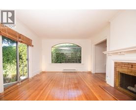 A large, empty room with wooden floors and a fireplace.
