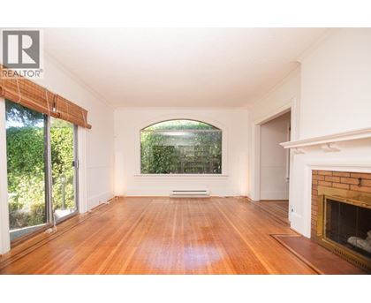 A large, empty room with wooden floors and a fireplace.