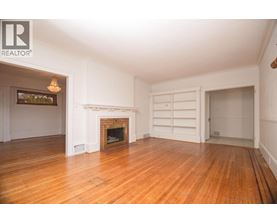 A large, empty room with a fireplace and a chandelier.