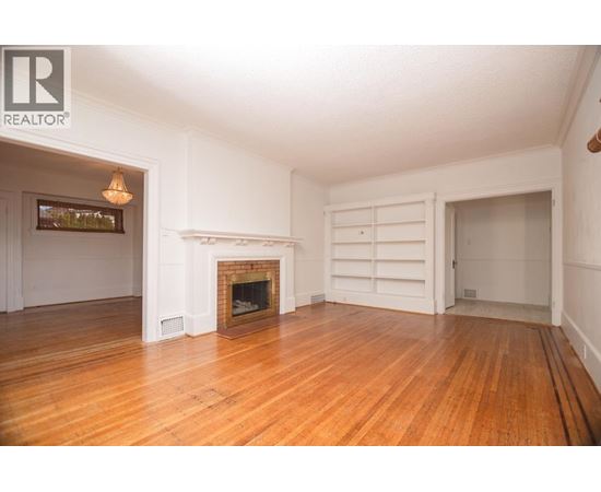 A large, empty room with a fireplace and a chandelier.