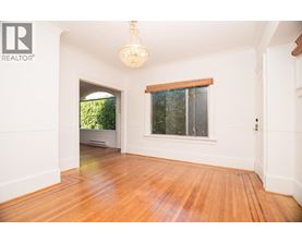 A room with wooden floors and a window with a view of trees.