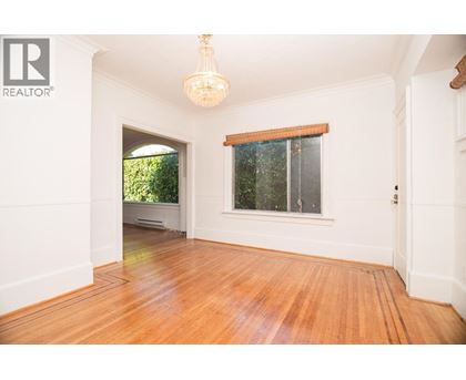 A room with wooden floors and a window with a view of trees.