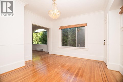 A room with wooden floors and a window with a view of trees.