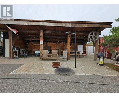 A wooden porch with a black pole and a white wheel hanging from it.