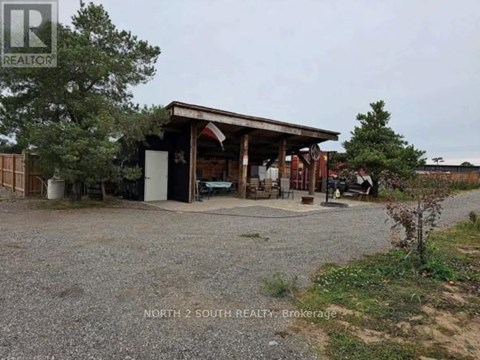 A gravel area with a building and a tree in the background.