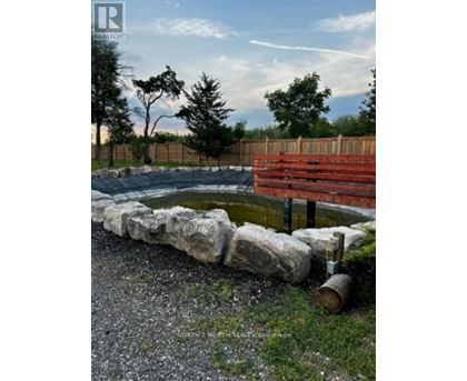 A small pond surrounded by rocks and a wooden fence.
