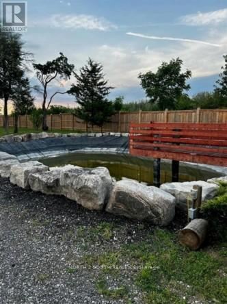 A small pond surrounded by rocks and a wooden fence.