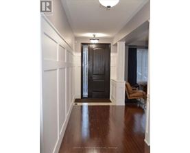 A hallway with a black door and a brown floor.