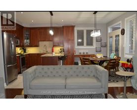 A kitchen with a grey couch and wooden cabinets.
