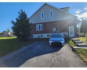 A blue car is parked in front of a house.