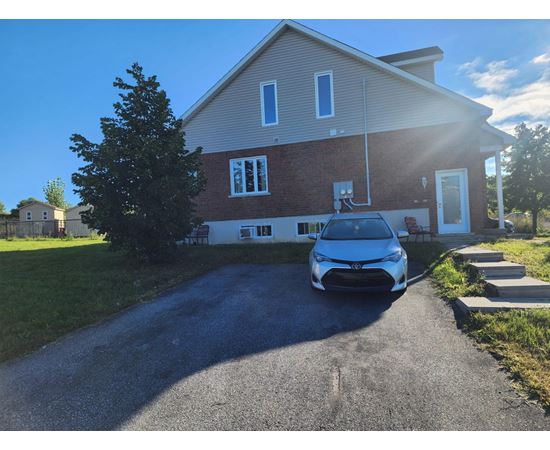 A blue car is parked in front of a house.