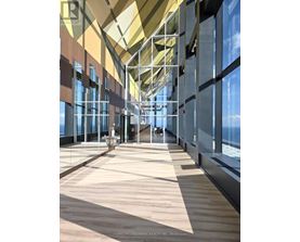 A long hallway with a glass wall on one side and a wooden floor.
