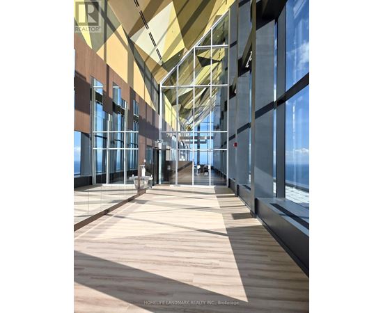 A long hallway with a glass wall on one side and a wooden floor.