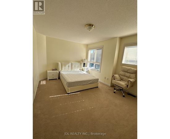 A bedroom with a bed, chair, and nightstand.