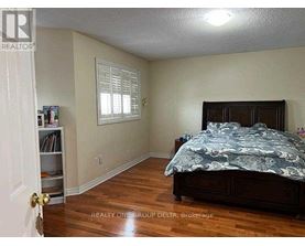 A bedroom with a bed, a window with blinds, and a bookcase.