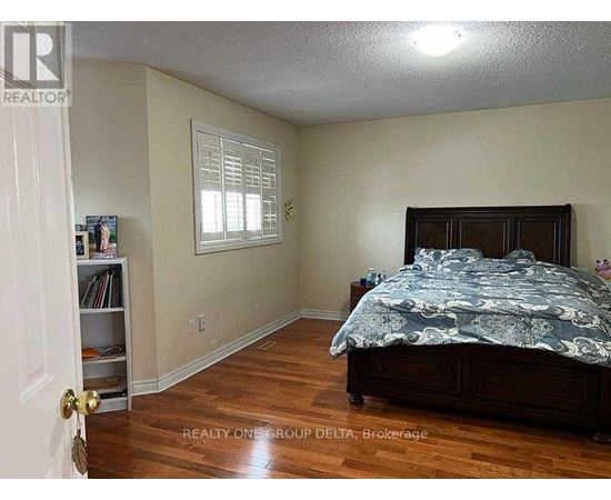 A bedroom with a bed, a window with blinds, and a bookcase.