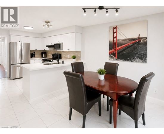 A dining room with a table and chairs and a picture of the Golden Gate Bridge on the wall.