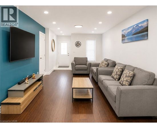 A living room with a grey couch and a flat screen TV mounted on the wall.