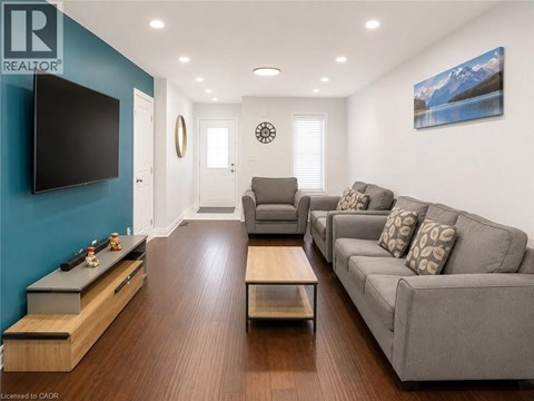 A living room with a grey couch and a flat screen TV mounted on the wall.