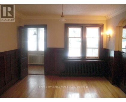 A room with wood floors and a window with a view of a building.