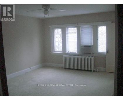A room with a ceiling fan and a radiator beneath a window.