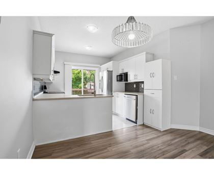 A kitchen with white cabinets and a wooden floor.