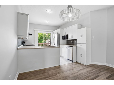 A kitchen with white cabinets and a wooden floor.