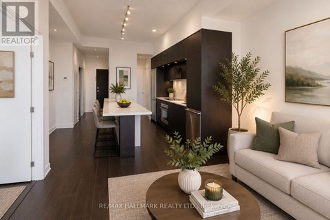 A modern living room with a white sofa, a coffee table, and a large painting on the wall.