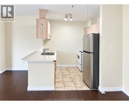 A kitchen with a white counter top and a stainless steel refrigerator.