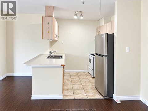 A kitchen with a white counter top and a stainless steel refrigerator.