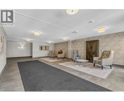 A spacious living room with a grey rug and patterned wallpaper.