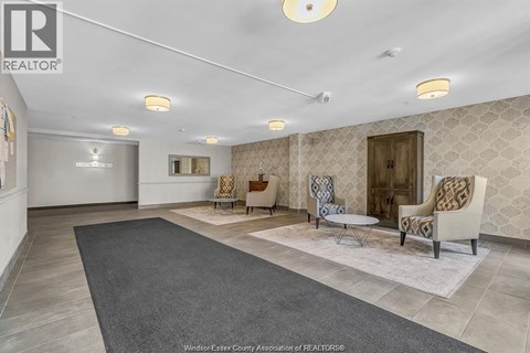 A spacious living room with a grey rug and patterned wallpaper.