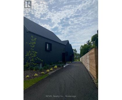 A modern house with a dark grey exterior and a wooden fence on the right side.