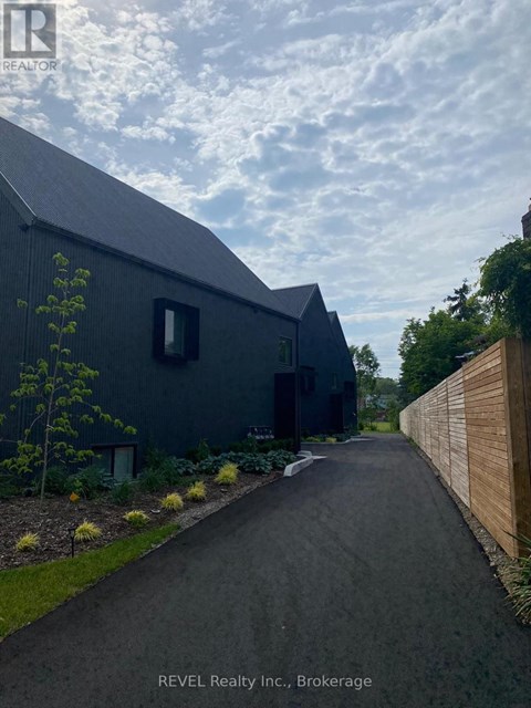 A modern house with a dark grey exterior and a wooden fence on the right side.