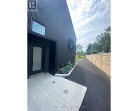 A modern house with a black exterior and a wooden fence in the background.