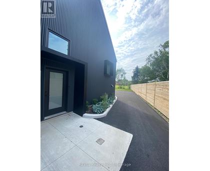 A modern house with a black exterior and a wooden fence in the background.
