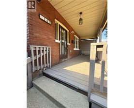 A porch with a wooden floor and a brick wall.