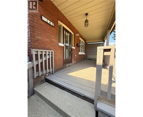 A porch with a wooden floor and a brick wall.
