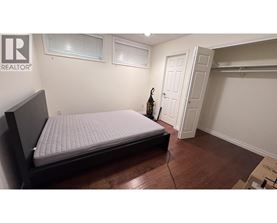 A bedroom with a bed, wooden floors, and a white door.