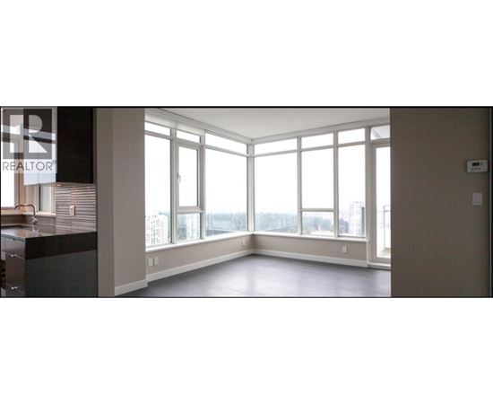 A large empty room with a view of the city through the windows.