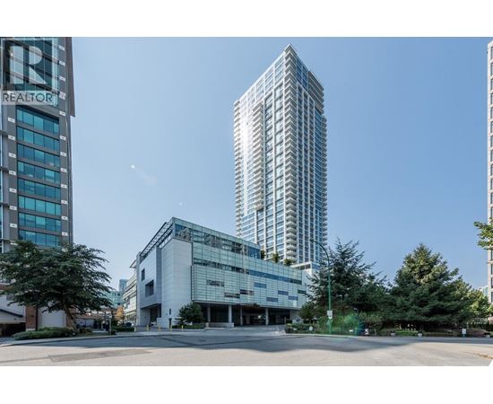 A modern building with a glass facade stands in front of a tall tree.