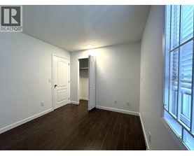 A room with a wooden floor and white walls, with a doorway leading to another room.