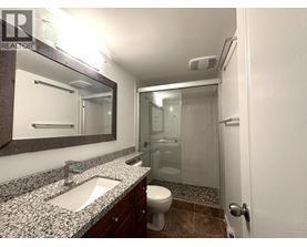 A bathroom with a sink, mirror, toilet and shower.