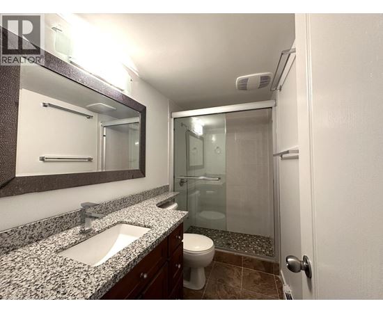 A bathroom with a sink, mirror, toilet and shower.