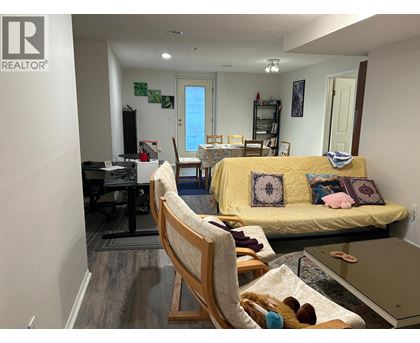 A living room with a yellow couch and a wooden chair.