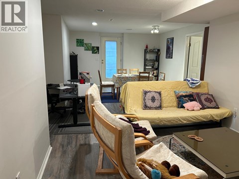 A living room with a yellow couch and a wooden chair.