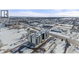 A winter scene with a large building in the center and a parking lot in the foreground.