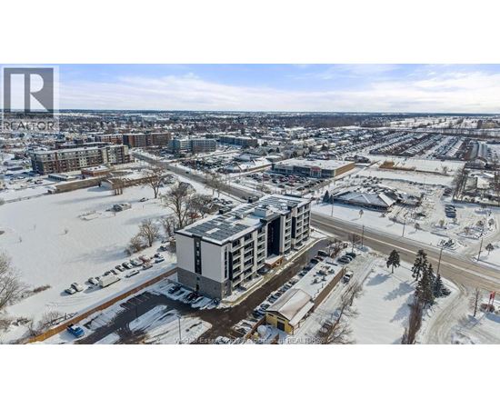 A winter scene with a large building in the center and a parking lot in the foreground.